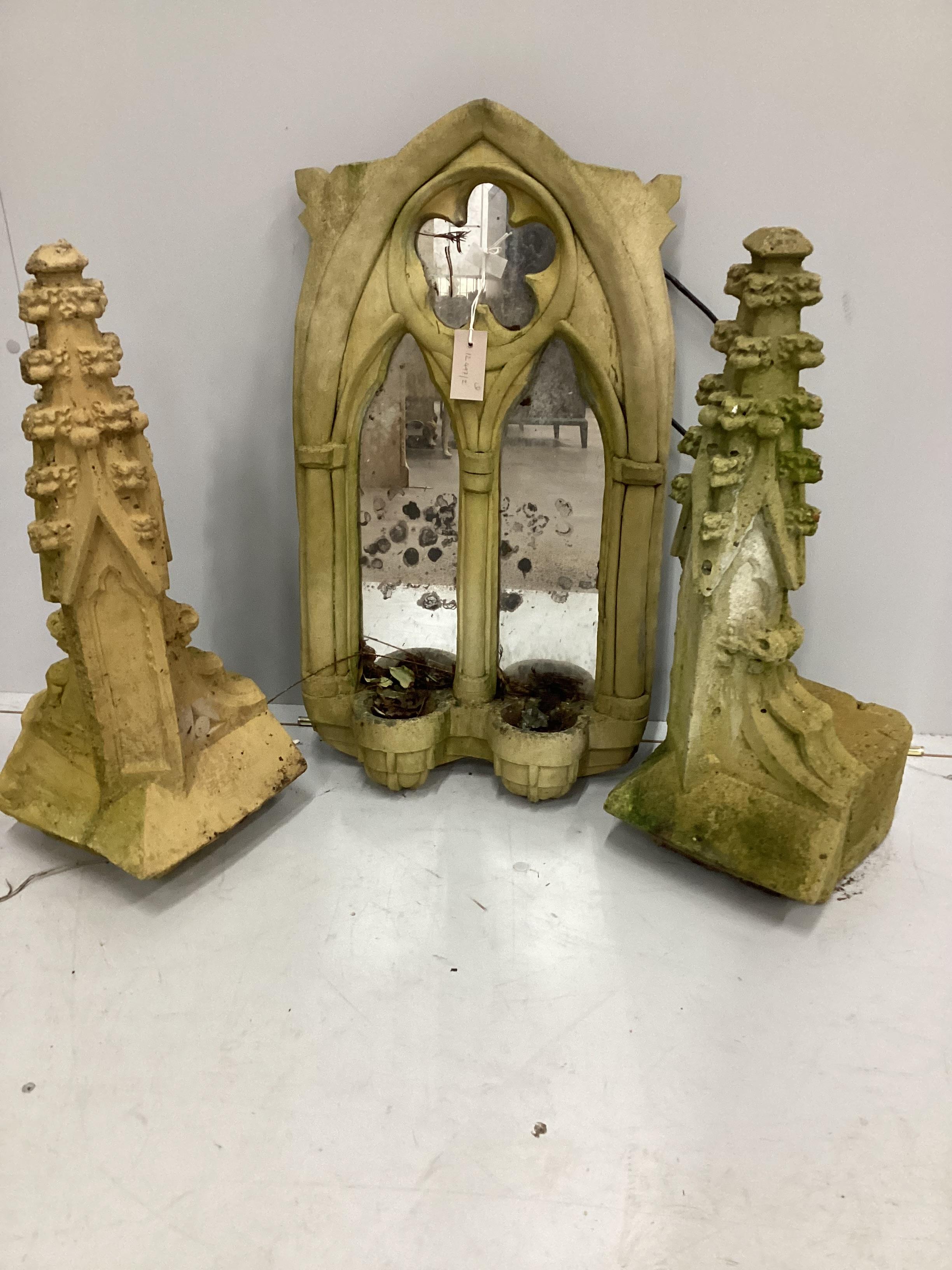 A cast stone Gothic style garden wall mirror, height 73cm together with a pair of cast stone finials